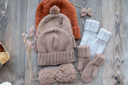 New handmade project, woolen mittens and hat, on dark wooden background
