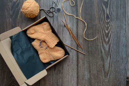 Packing small orange color baby socks, made of organic sheep wool