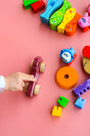 Child is playing with colorful wooden and plastic toys, on pink backgroundの写真素材
