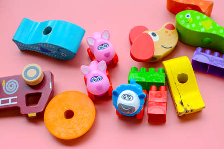 Child is playing with colorful wooden and plastic toys, on pink backgroundの写真素材