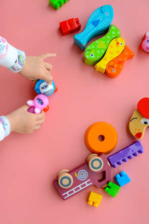 Child is playing with colorful wooden and plastic toys, on pink backgroundの写真素材