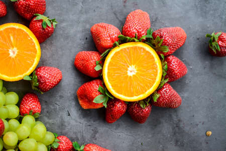 Various fruits and berries for healthy breakfast, on dark background in the kitchenの写真素材