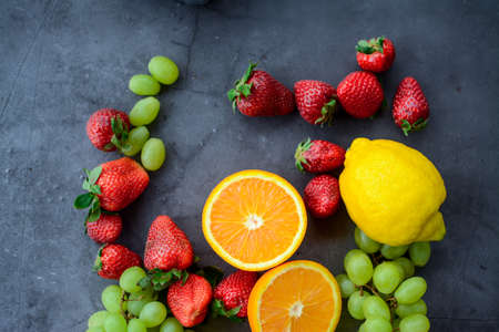 Various fruits and berries for healthy breakfast, on dark background in the kitchenの写真素材