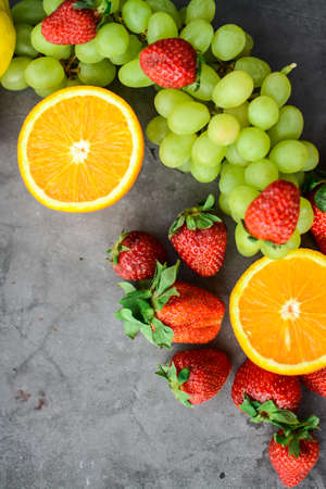 Various fruits and berries for healthy breakfast, on dark background in the kitchenの写真素材