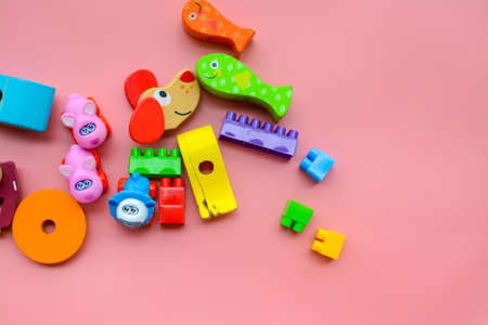 Child is playing with colorful wooden and plastic toys, on pink backgroundの写真素材