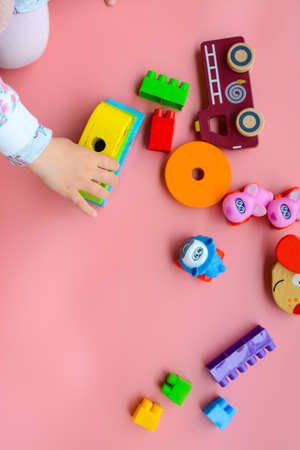 Child is playing with colorful wooden and plastic toys, on pink backgroundの写真素材