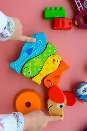 Child is playing with colorful wooden and plastic toys, on pink backgroundの写真素材