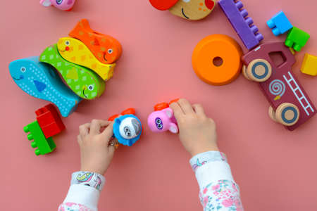 Child is playing with colorful wooden and plastic toys, on pink backgroundの写真素材