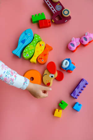 Child is playing with colorful wooden and plastic toys, on pink backgroundの写真素材
