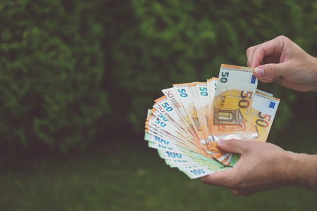 Euro banknotes in man hands, green backgroundの写真素材