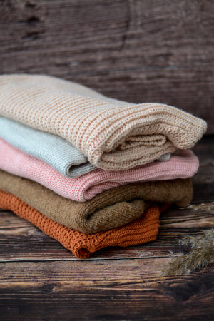The pile of knitted sweaters on dark brown backgroundの写真素材