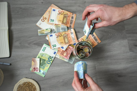 Man putting euro banknotes and coins into the jarの写真素材
