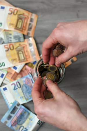 Man putting euro banknotes and coins into the jarの写真素材