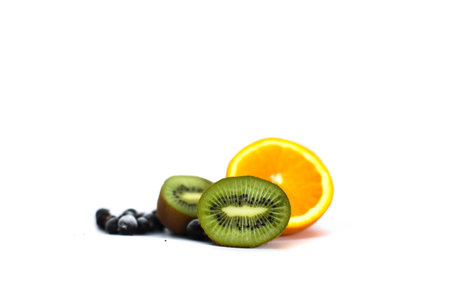 Kiwi fruit, black currants and orange on light backgroundの写真素材