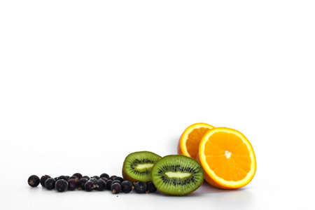 Kiwi fruit, black currants and orange on light backgroundの写真素材