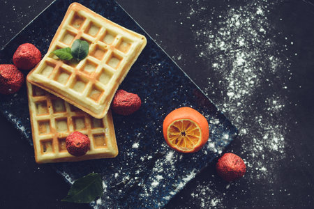 Belgian waffles with chocolate and strawberries on dark background, top viewの写真素材