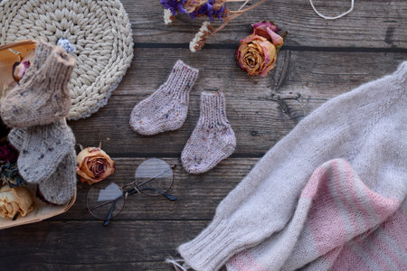 Woolen socks, glasses and dried flowers on a wooden background