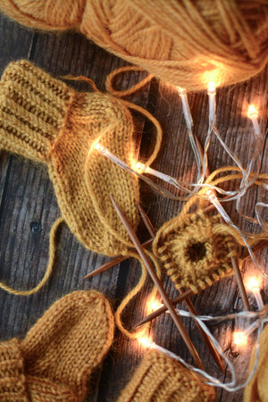 Knitted baby booties with Christmas lights on rustic wooden backgroundの写真素材