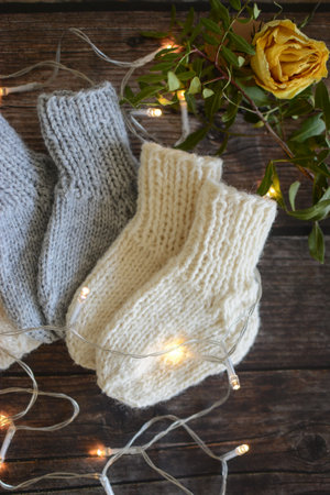 Handmade knitted socks on a wooden background with a garland.