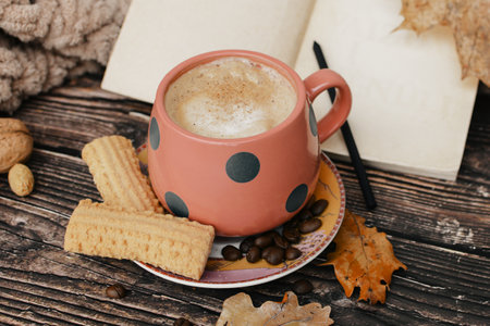 Cup of coffee with cookies and autumn leaves on a wooden backgroundの写真素材