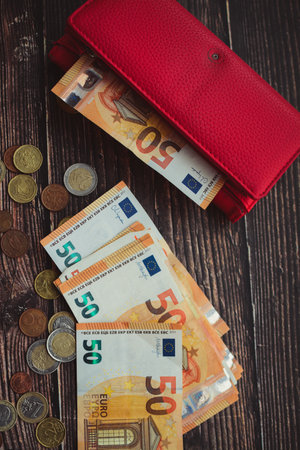 Euro banknotes and coins in a red wallet on a wooden backgroundの写真素材