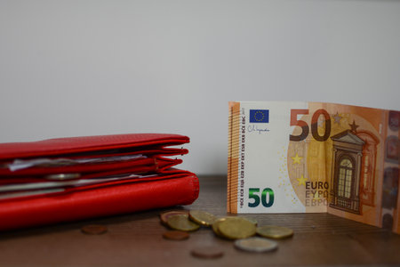Euro banknotes in a red wallet and coins on a wooden tableの写真素材
