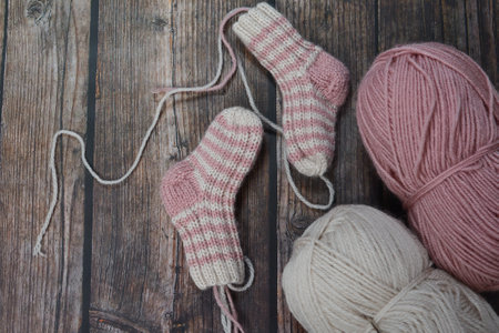 Knitting woolen socks on a wooden background. Knitting needles and woolen socks.