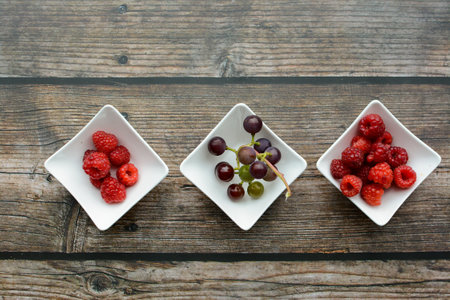 Raspberry, currant and gooseberry in a bowl on wooden backgroundの写真素材