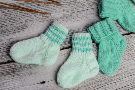 Pair of baby socks and knitting needles on rustic wooden backgroundの写真素材