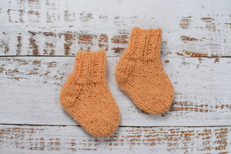 A pair of knitted baby socks on a white wooden background.の写真素材