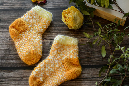 Woolen socks and a bouquet of yellow roses on a wooden backgroundの写真素材