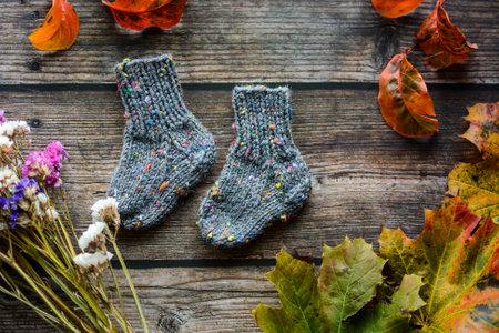 Woolen socks on a wooden background with autumn leaves and flowersの写真素材