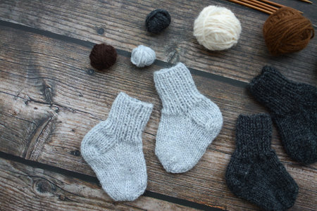 knitted socks and wool balls on a wooden background, top view