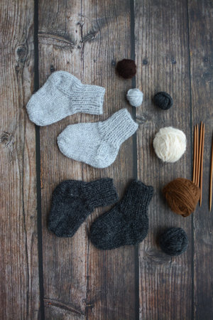 Woolen socks, knitting needles and balls of yarn on wooden background