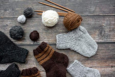 Woolen socks, knitting needles and balls of yarn on wooden backgroundの写真素材