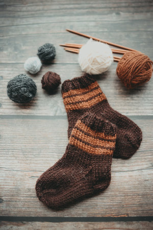Woolen socks with knitting needles and balls of yarn on wooden backgroundの写真素材