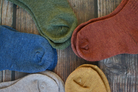 A collection of different socks on a wooden background. Top view.の写真素材