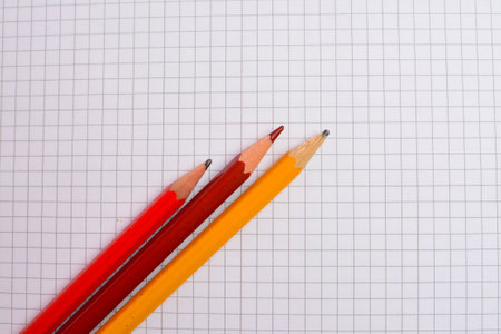 Colored pencils on a sheet of paper with a grid backgroundの写真素材