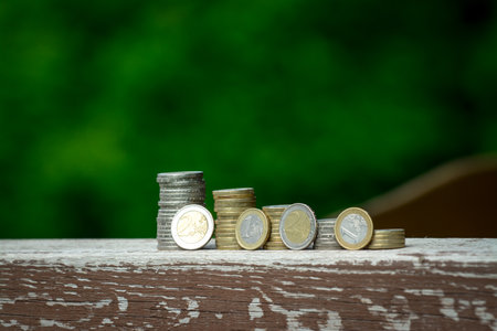 Coins stacked on each other on wooden table with blur green backgroundの写真素材