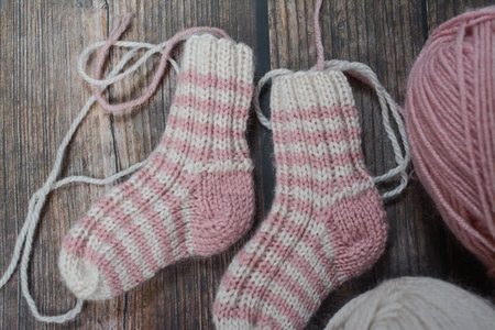 Pair of knitted socks with wool threads on old wooden backgroundの写真素材