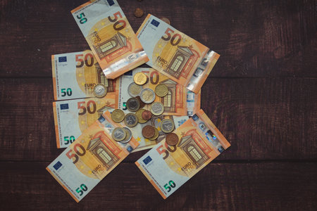 Euro banknotes and coins on a wooden background. Top view.