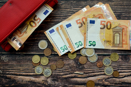 Euro banknotes and coins in a red wallet on a wooden backgroundの写真素材
