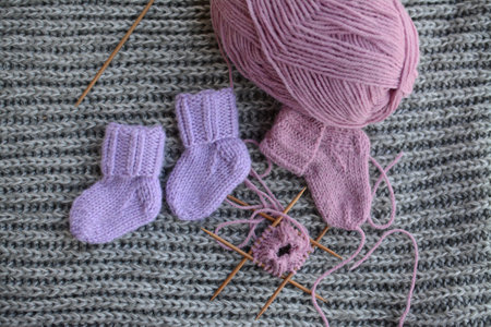 Knitting with woolen socks and needles on grey knitted backgroundの写真素材