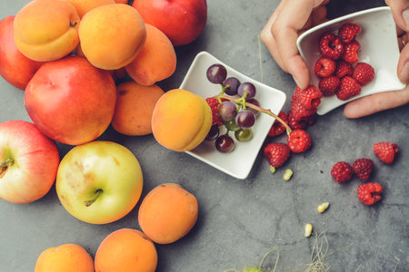Close up of woman hands holding bowl with fresh fruits. Top view