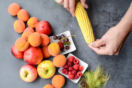 Woman hands holding fresh fruits on gray background. Healthy food concept.