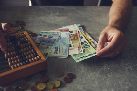 Businessman counting money on table with abacus and euro banknotesの写真素材