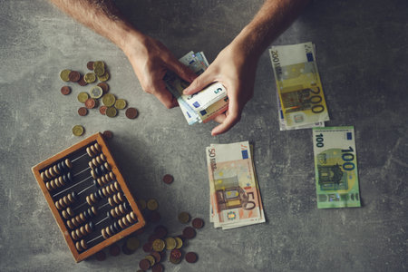 Man counting money with abacus and euro banknotes on grey background