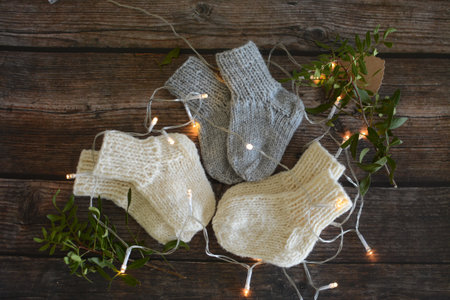 Warm knitted socks on a rustic wooden background with garland lightsの写真素材