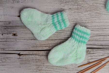 Knitted socks and needles on a wooden background. View from above.