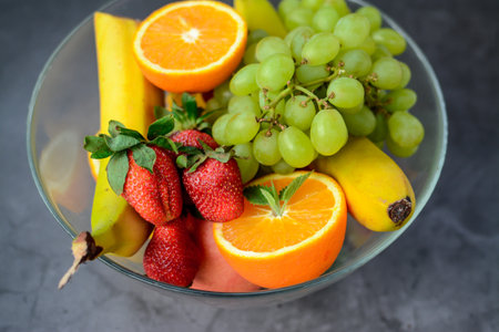 Mix of fresh fruits in a glass bowl on a gray background.の写真素材